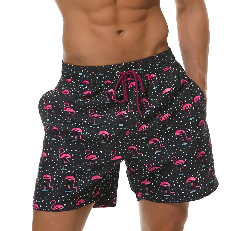 Short de bain homme noir porté – motifs flamants roses fun, coupe droite et poches latérales visibles