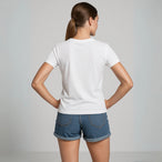 Vue arrière d’un tee-shirt femme blanc porté par mannequin avec short en jean, fond studio gris clair