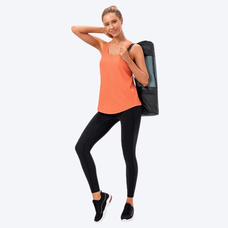 Femme en tenue de yoga avec débardeur orange, legging noir et sac de tapis de yoga