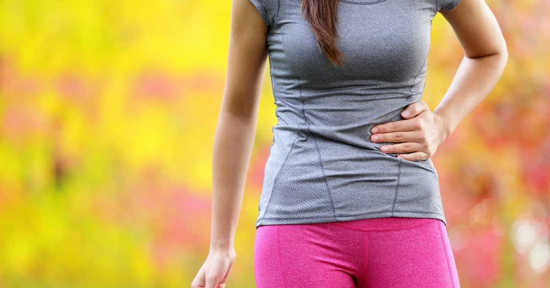 Femme en tenue de running tenant son flanc à cause d’un point de côté en course à pied