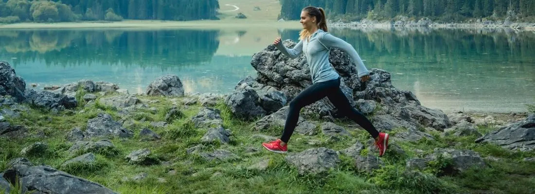 Coureuse en plein air améliorant sa foulée sur terrain naturel avec une posture dynamique et efficace.