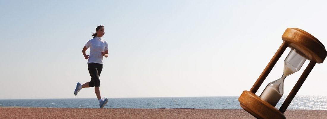 Coureur au bord de la mer avec un sablier symbolisant l’objectif de courir 5 km en moins de 25 minutes