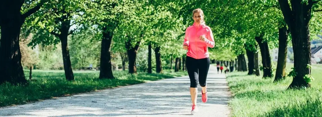 Femme faisant du jogging quotidien dans un parc avec arbres, entraînement santé et bien-être
