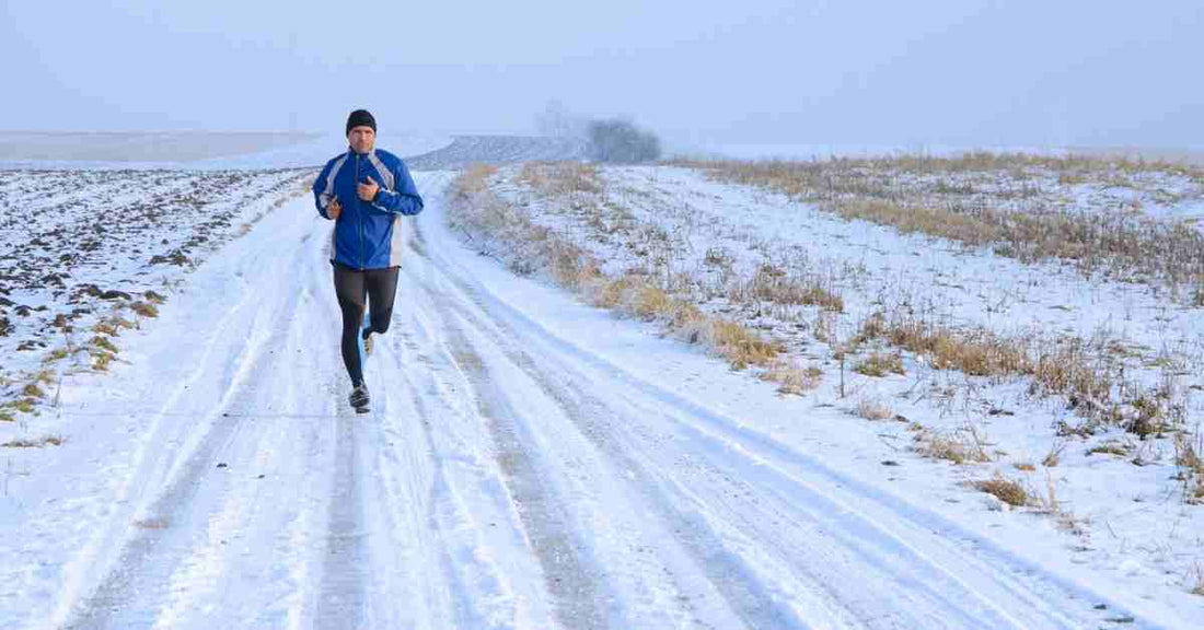 coureur en tenue running hiver sur route enneigée avec veste thermique et équipement contre le froid