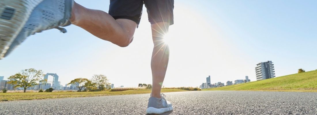 Coureur en plein mouvement montrant une foulée avant-pied sur route ensoleillée – comparaison avec attaque talon pour la course à pied