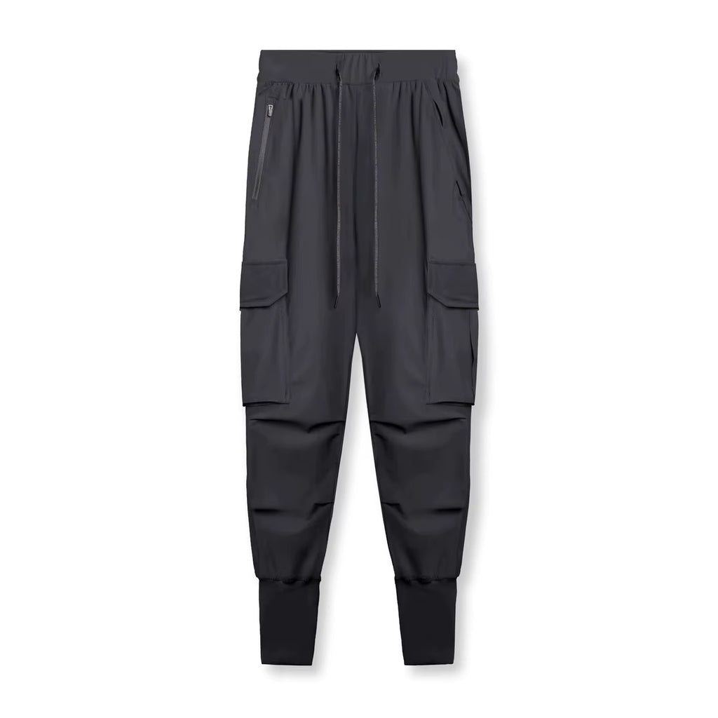 Pantalon running homme Noir Anthracite conçu en tissu technique stretch nylon & spandex. Sa coupe ajustée tapered, ses poches cargo fonctionnelles et son bas élastiqué offrent maintien, mobilité et style minimaliste en training urbain.

