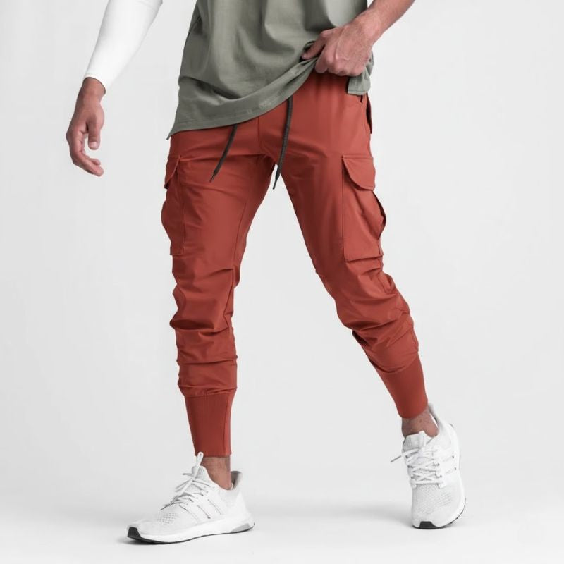 Pantalon running homme Terracotta Intense conçu en nylon & spandex stretch. Sa coupe tapered avec poches cargo fonctionnelles et bas resserré offre mobilité, maintien et style sport affirmé.
