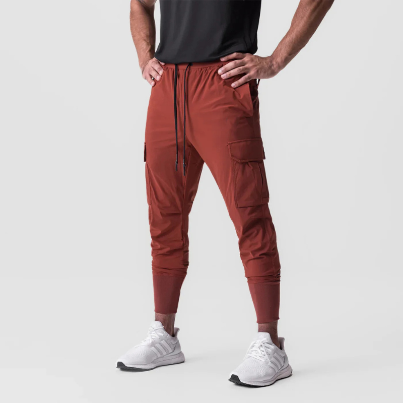 Pantalon running homme Terracotta Intense conçu en tissu technique stretch nylon & spandex. Sa coupe tapered avec poches cargo fonctionnelles et bas resserré assure mobilité, maintien et style sport affirmé.
