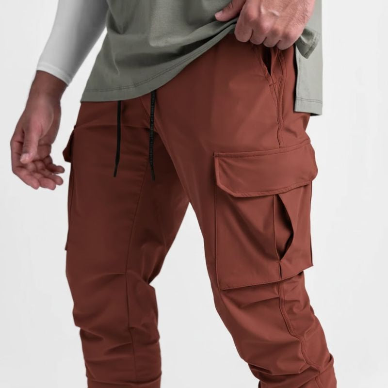 Pantalon running homme Terracotta Intense conçu en nylon & spandex stretch pour une liberté totale de mouvement. Sa coupe tapered avec poches cargo structurées et finition bas resserré assure mobilité, maintien et style affirmé.
