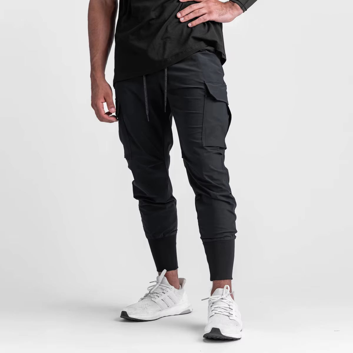 Pantalon running homme Noir Performance, conçu en nylon & spandex stretch pour accompagner chaque mouvement. Sa coupe tapered avec poches cargo et finition bas élastiqué offre stabilité, confort et style minimaliste en training urbain.
