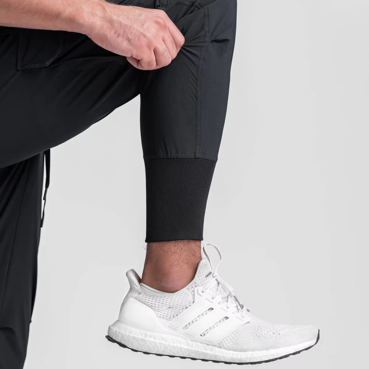 Pantalon running homme Noir Performance conçu en tissu technique stretch nylon & spandex. Sa coupe tapered avec bas élastiqué assure maintien, mobilité et style minimaliste pour fitness et training urbain.
