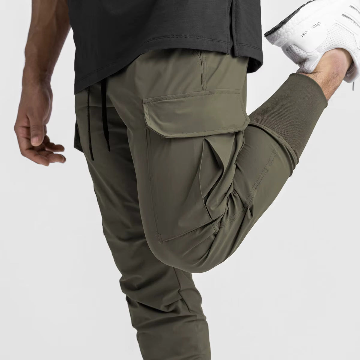Pantalon running homme coloris Kaki Olive, conçu en nylon et spandex stretch pour une liberté totale de mouvement. Coupe ajustée, poche cargo fonctionnelle et cordon de serrage pour un maintien précis. Idéal fitness, musculation, entraînement outdoor et style sport utilitaire moderne.
