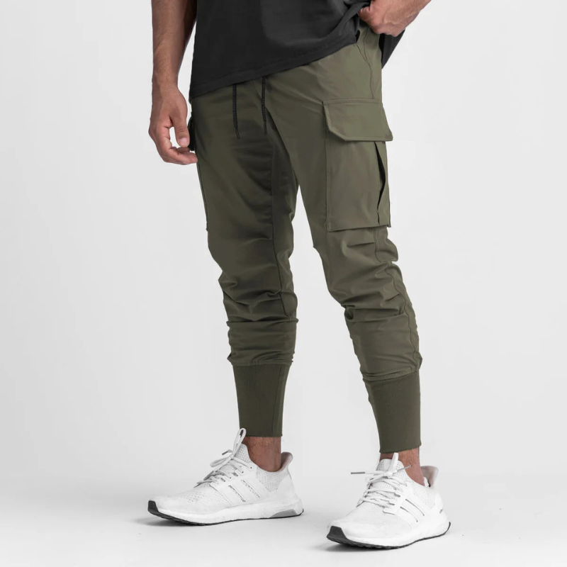 Pantalon running homme coloris Olive Tactical. Tissu stretch nylon & spandex, coupe ajustée, cordon de serrage et longueur complète. Idéal pour fitness, musculation et entraînement outdoor.
