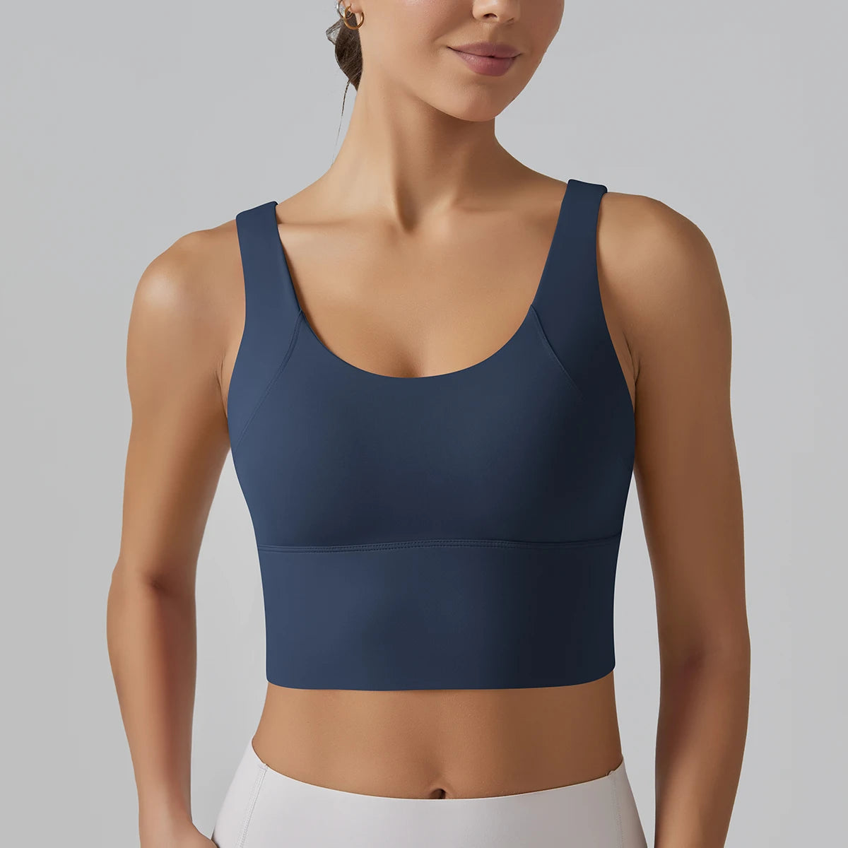 Débardeur sport femme bleu marine Deep Navy avec soutien et coupe gainante, vue bras sur hanche.