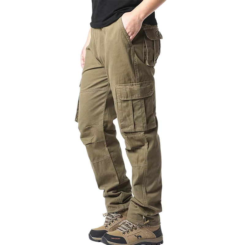Pantalon cargo homme coton vert armée porté de profil, coupe loose multi-poches, style randonnée et travail extérieur
