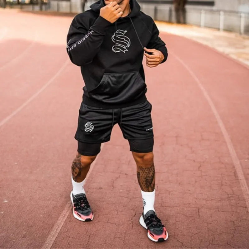 Short running homme noir 2 en 1 avec compression intégré porté en tenue complète sur piste d’athlétisme
