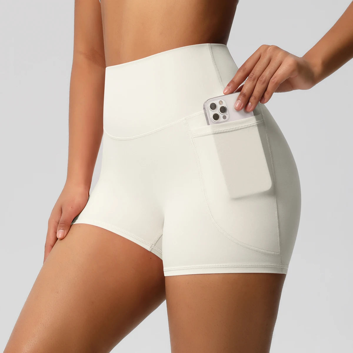 Short sport femme taille haute ivoire, vue de face, coupe gainante et confortable pour fitness et yoga.
