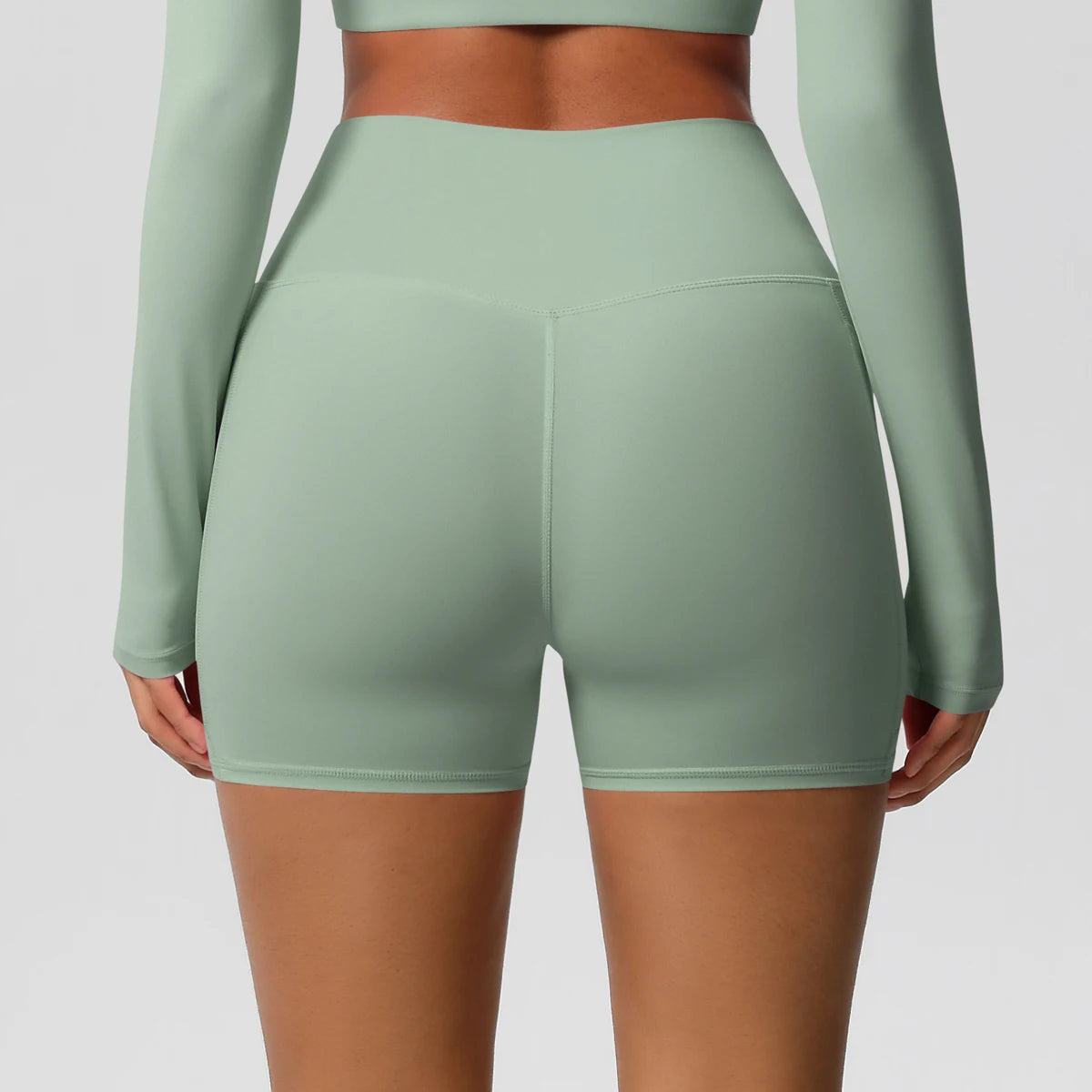 Vue dos du short sport femme taille haute vert clair, maintien optimal et tissu extensible adapté à l’entraînement.
