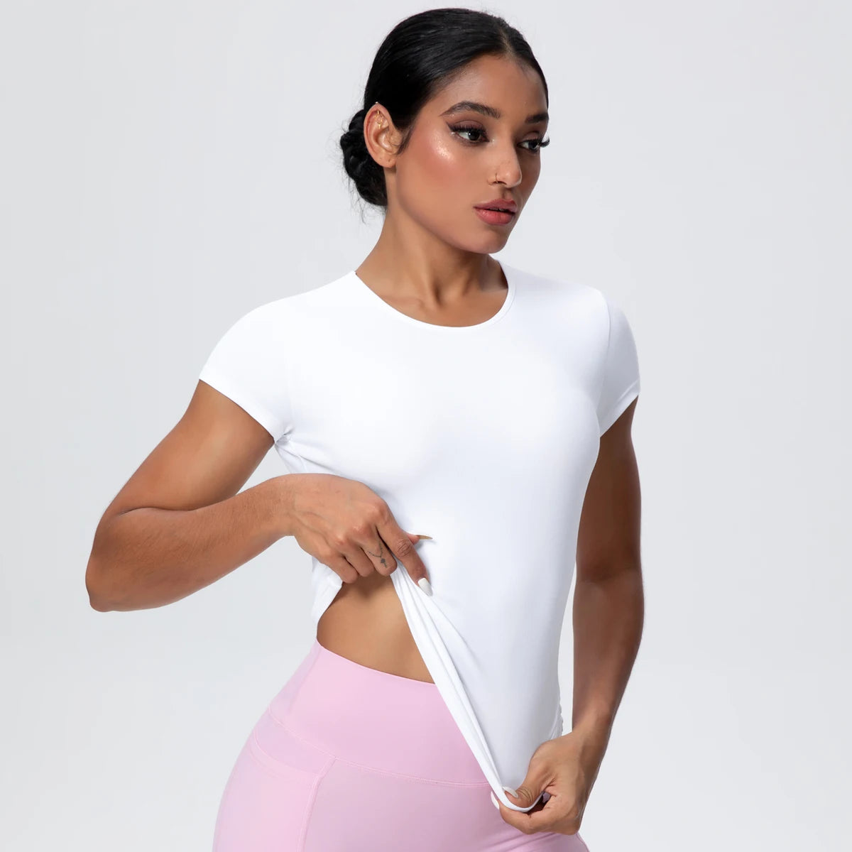 T-shirt de sport femme Arctic Ivory en démonstration d’élasticité, coupe gainante, tissu respirant et extensible.