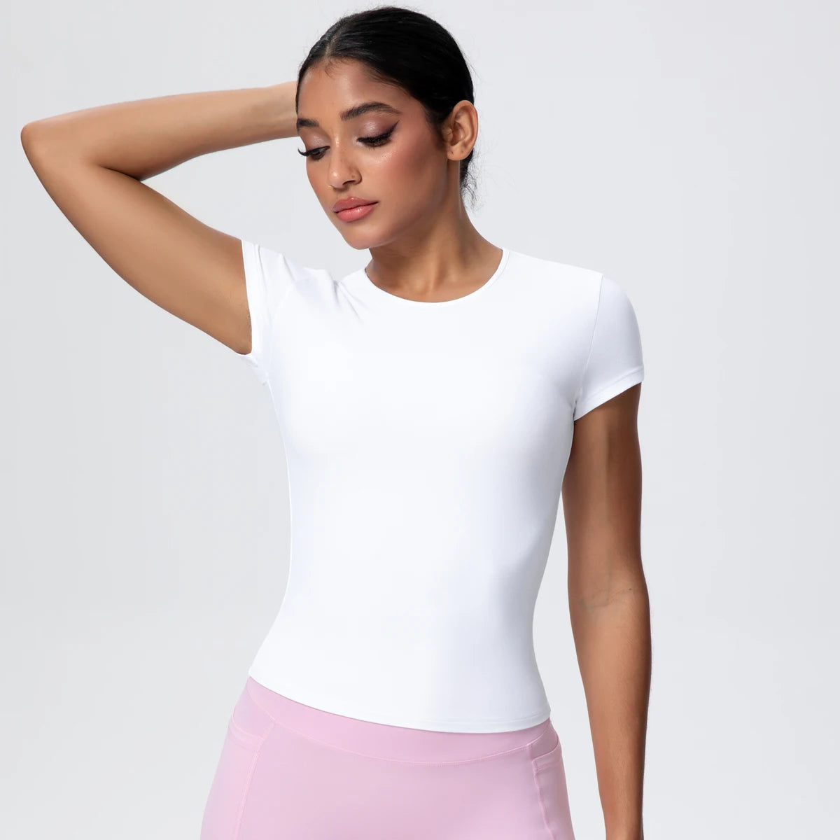 T-shirt de sport femme Arctic Ivory en vue de face, bras levé, coupe gainante, tissu respirant et extensible.