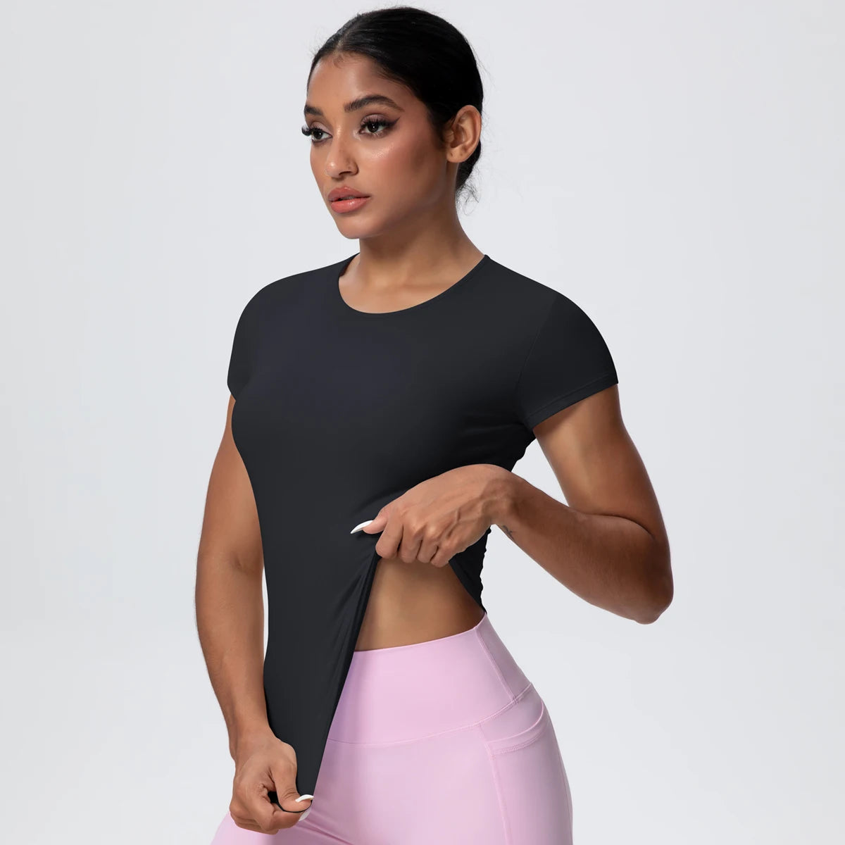 T-shirt de sport femme Carbon Shadow en vue de face, démonstration d’élasticité, coupe gainante, tissu respirant et extensible.