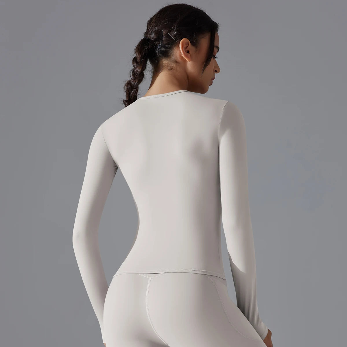 T-shirt de sport femme manches longues gris clair, coupe slim et tissu stretch respirant pour fitness, yoga et running.