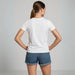 Vue arrière d’un tee-shirt femme blanc porté par mannequin avec short en jean, fond studio gris clair