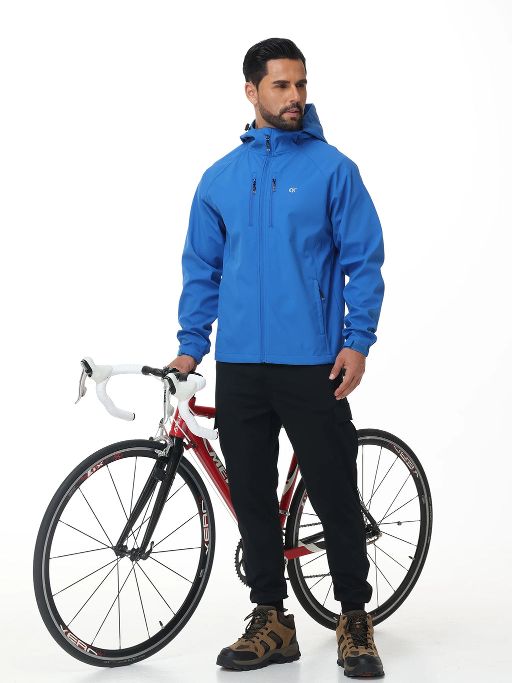 Homme portant une veste randonnée coupe vent bleue à côté d’un vélo pour activité outdoor
