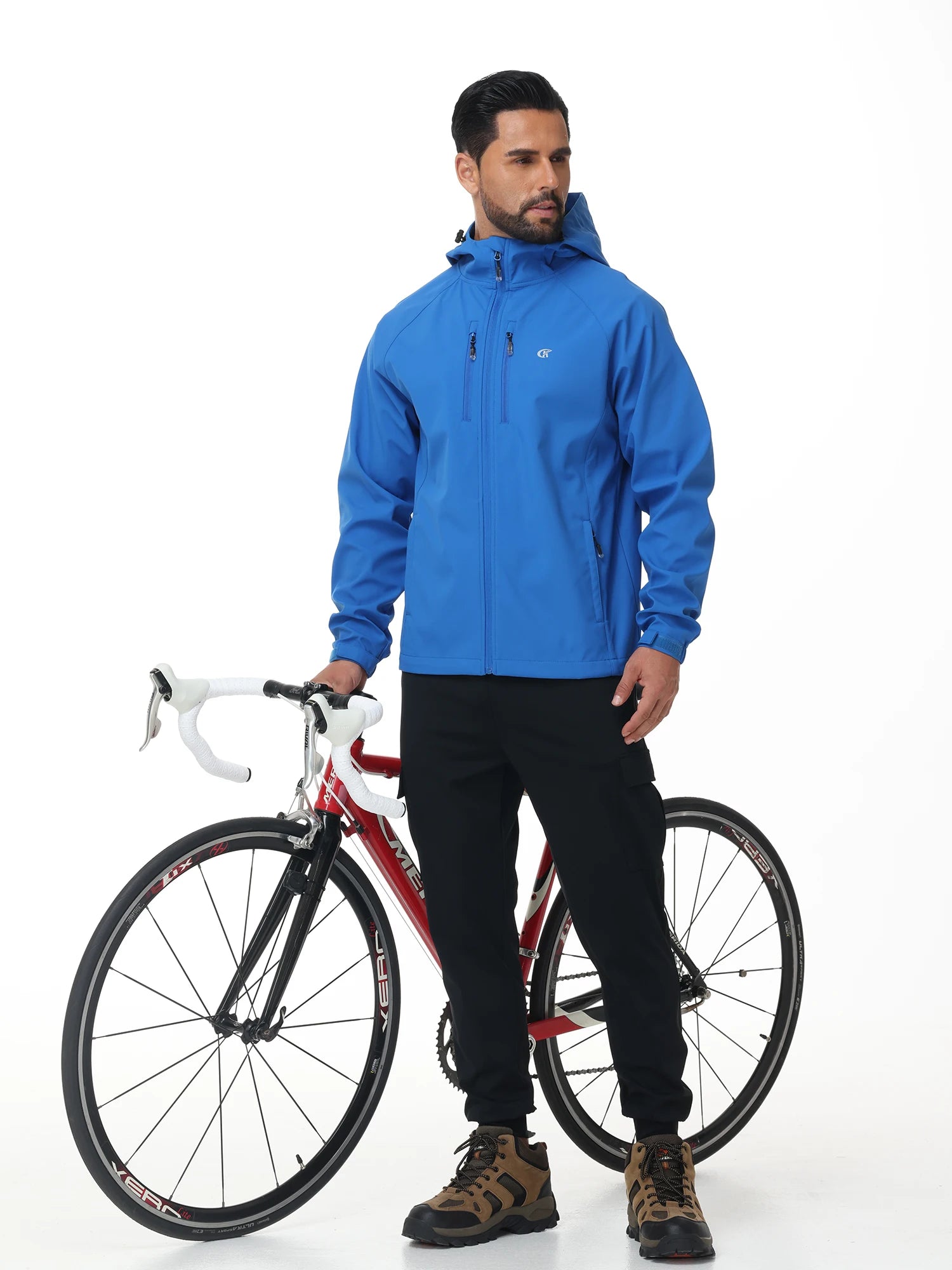 Homme portant une veste randonnée coupe vent bleue à côté d’un vélo pour activité outdoor