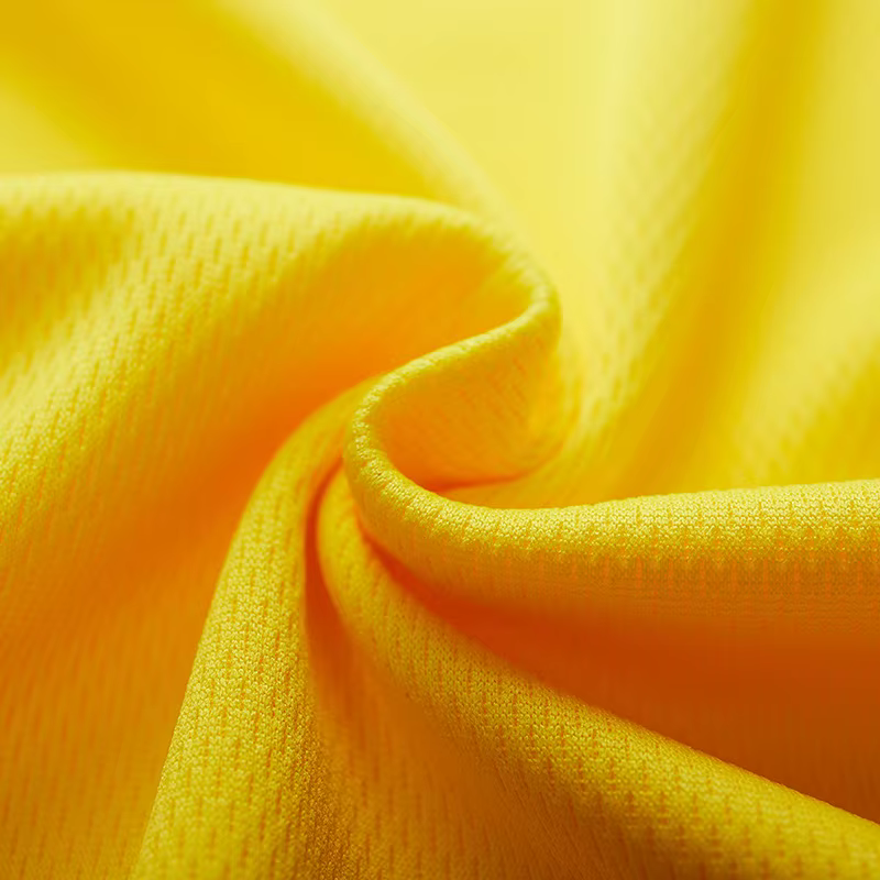 Gros plan sur la matière polyester respirante du t-shirt sport jaune, texture technique ultra légère et douce, idéale pour le running et le fitness